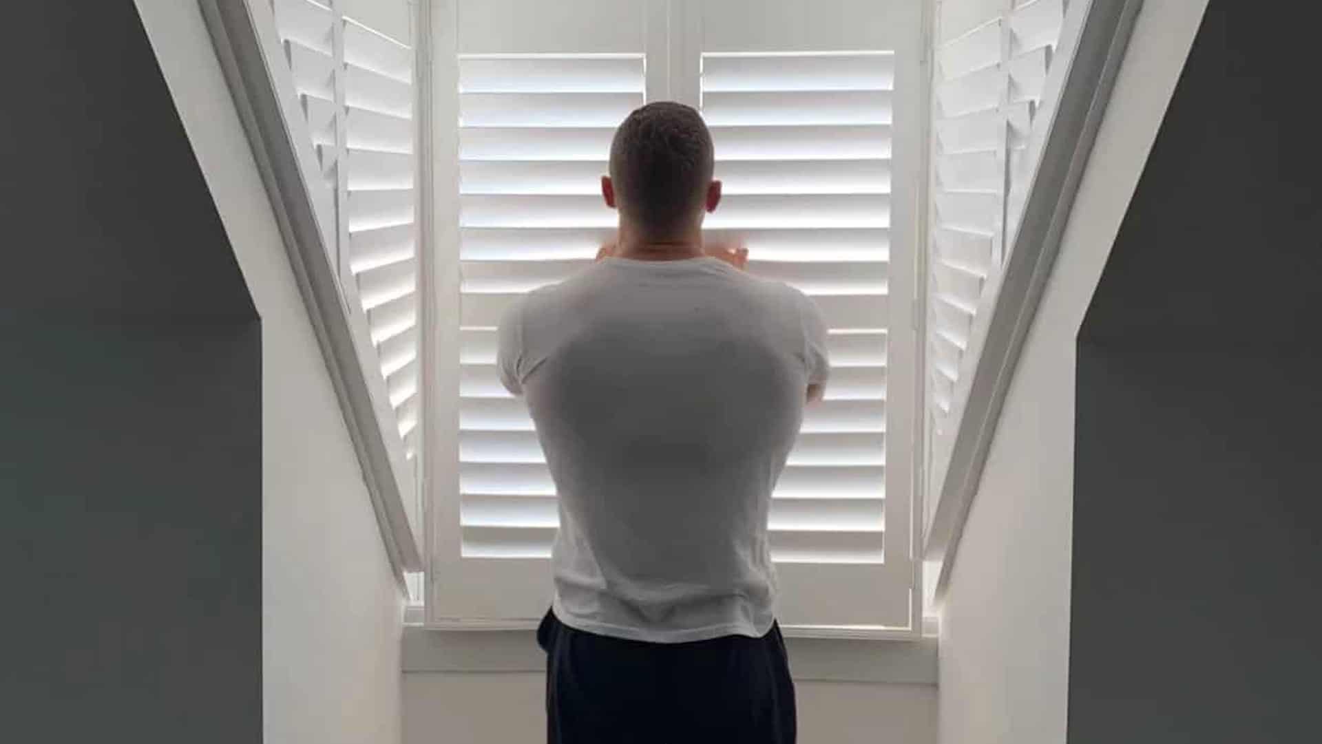 A man is looking at window shutters.